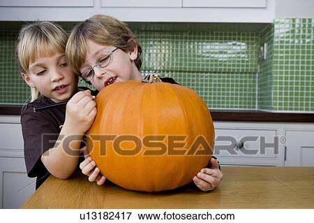 Little girl and boy making a pumpkin lantern. View Large Photo Image Stock Photo - Little girl and boy making a pumpkin lantern. . Fotosearch