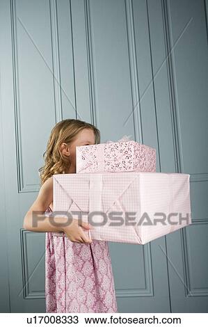 Stock Image - little girl carrying pile presents face obscured. Fotosearch