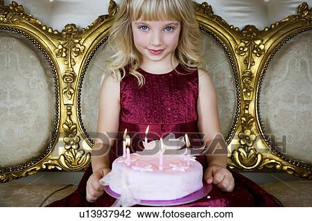 Stock Image - Little girl holding a birthday cake with lit candles. Fotosearch