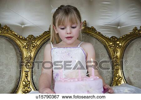 Stock Photo - Little girl holding a birthday cake with lit candles. Fotosearch