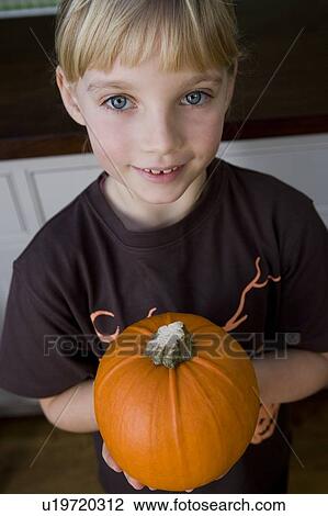 Stock Image - Little girl holding an orange Hallowe'en pumpkin. Fotosearch