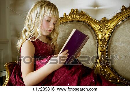 Stock Photograph - Little girl in a party dress, reading a book. Fotosearch