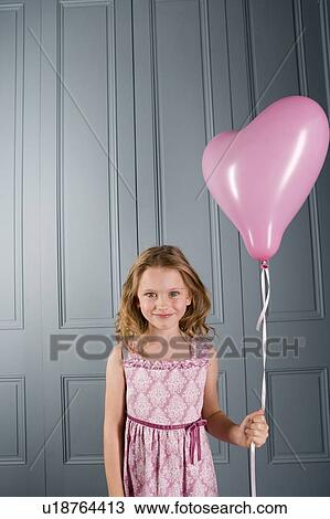 Stock Image - little girl in party dress holding pink heart shaped balloon. Fotosearch