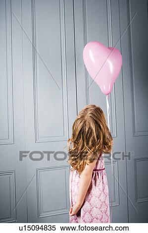 little girl in party dress looking at her pink heart shaped balloon View Large Photo Image Stock Photography - little girl in party dress looking at her pink heart shaped balloon. Fotosearch