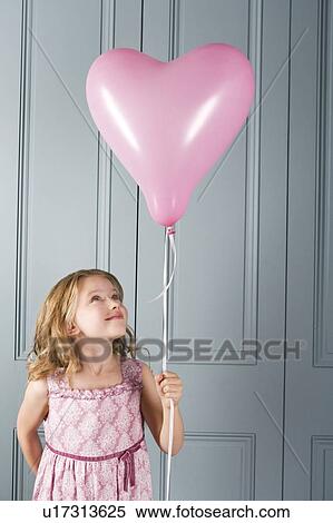 little girl in party dress looking at her pink heart shaped balloon View Large Photo Image Stock Photography - little girl in party dress looking at her pink heart shaped balloon. Fotosearch