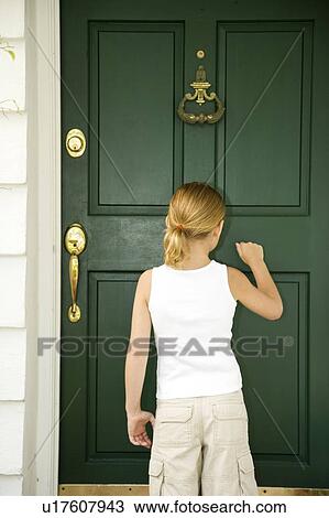 Stock Image - Little girl knocking at the front door of a house. Fotosearch