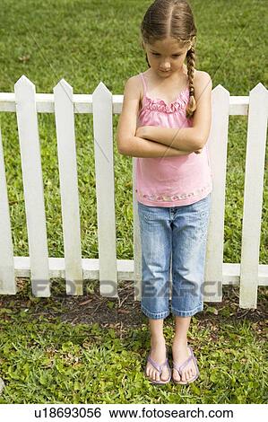 little girl standing against fence with arms folded View Large Photo Image Stock Photograph - little girl standing against fence with arms folded. Fotosearch