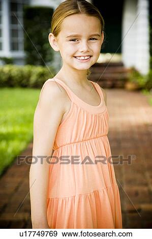 Stock Photo - Little girl standing on the garden path outside her new home. Fotosearch