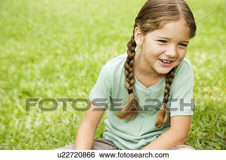 Stock Photograph - little girl with pigtails sitting on the grass. Fotosearch