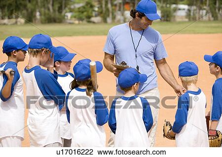Stock Image - Little league baseball team and coach on pitch. Fotosearch