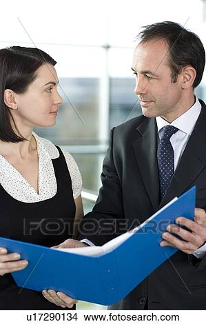 Picture - Male and female business colleagues looking at notes in a folder. Fotosearch
