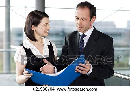 Picture - Male and female business colleagues looking at notes in a folder. Fotosearch
