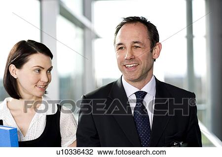 Male and female business colleagues chatting in office building View Large Photo Image Stock Image - Male and female business colleagues chatting in office building. Fotosearch