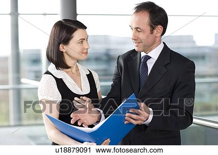 Stock Image - Male and female business colleagues looking at notes in a folder. Fotosearch