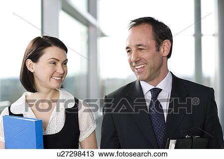 Male and female business colleagues chatting in office building View Large Photo Image Stock Image - Male and female business colleagues chatting in office building. Fotosearch