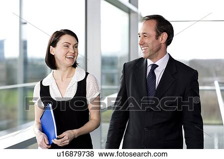 Male and female business colleagues chatting in office building View Large Photo Image Stock Photo - Male and female business colleagues chatting in office building. Fotosearch
