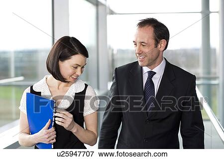 Stock Photo - Male and female business colleagues chatting in office building. Fotosearch