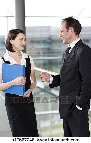 Male and female business colleagues chatting in office building View Large Photo Image Stock Photograph - Male and female business colleagues chatting in office building. Fotosearch