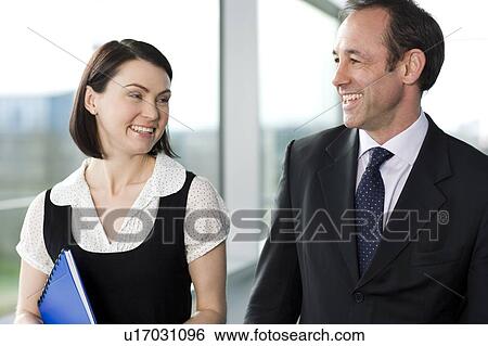 Stock Photograph - Male and female business colleagues chatting in office building. Fotosearch