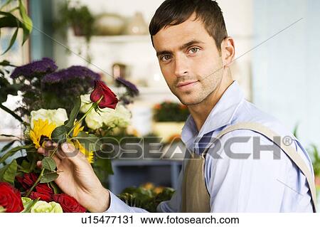 Stock Image - Male florist amongst the flowers in his shop. Fotosearch