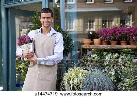 Stock Photo - Male florist arranging the plant display outside his shop. Fotosearch