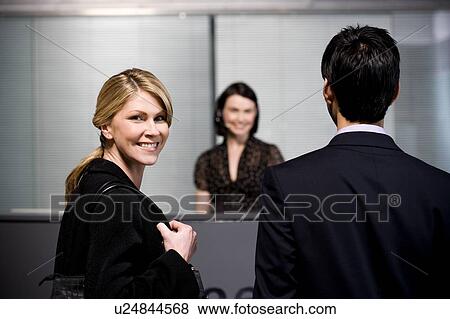 Stock Photo - Man and woman arrive at office reception for a business meeting. Fotosearch