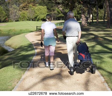 Stock Photo - Man and woman walking on a golf course. Fotosearch