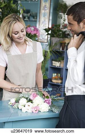 Man buying a bouquet of flowers in a florist's shop, flirting with the assistant View Large Photo Image Stock Photo - Man buying a bouquet of flowers in a florist's shop, flirting with the assistant. Fotosearch