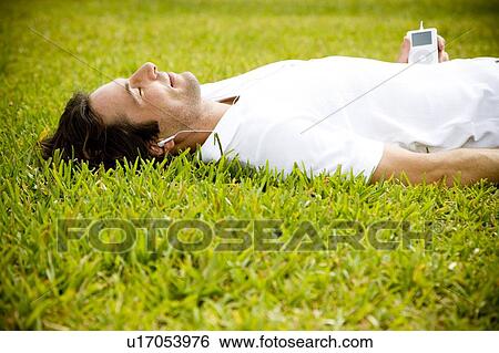 Stock Photograph - man lying on the grass listening to music. Fotosearch