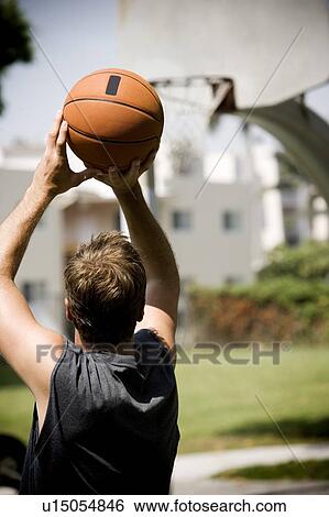 Stock Photograph - man shooting hoops on an urban basketball court . Fotosearch