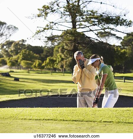 Stock Photograph - Man teaching a woman how to play golf. Fotosearch