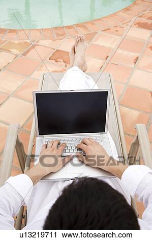 Man using a laptop by the pool View Large Photo Image Stock Image - Man using a laptop by the pool. Fotosearch