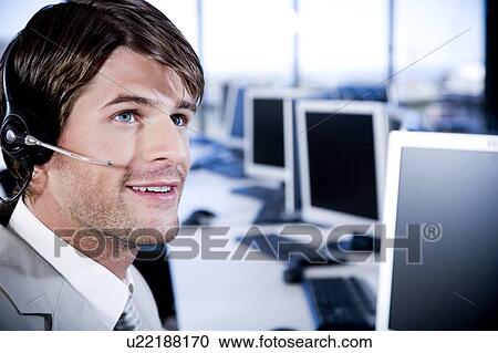 Man with a call centre headset on in a contemporary office View Large Photo Image Stock Image - Man with a call centre headset on in a contemporary office. Fotosearch
