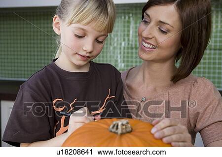 Mother and daughter carving a face in a Hallowe'en pumpkin View Large Photo Image Stock Image - Mother and daughter carving a face in a Hallowe'en pumpkin. Fotosearch