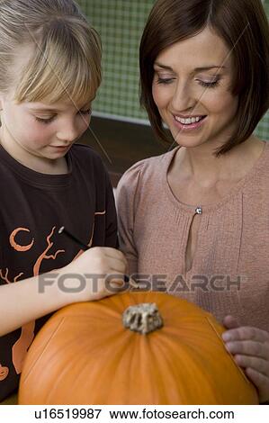 Mother and daughter carving a face in a Hallowe'en pumpkin View Large Photo Image Stock Photo - Mother and daughter carving a face in a Hallowe'en pumpkin. Fotosearch