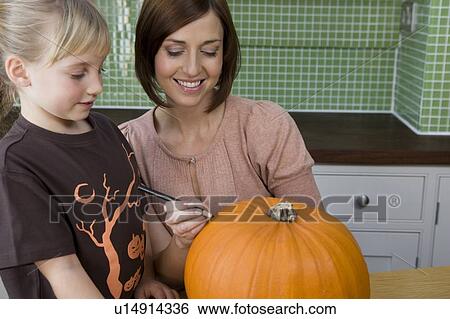Mother and daughter carving a face in a Hallowe'en pumpkin View Large Photo Image Stock Photograph - Mother and daughter carving a face in a Hallowe'en pumpkin. Fotosearch
