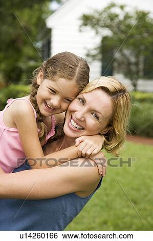 Stock Photograph - mother and daughter hugging and laughing in garden. Fotosearch