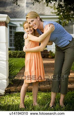 Mother and daughter hugging on the garden path outside their new home View Large Photo Image Stock Image - Mother and daughter hugging on the garden path outside their new home. Fotosearch