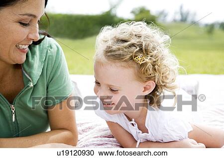 Stock Image - mother and daughter lying on picnic rug. Fotosearch