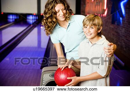 Stock Photo - Mother and son in a bowling alley, holding red bowling ball. Fotosearch