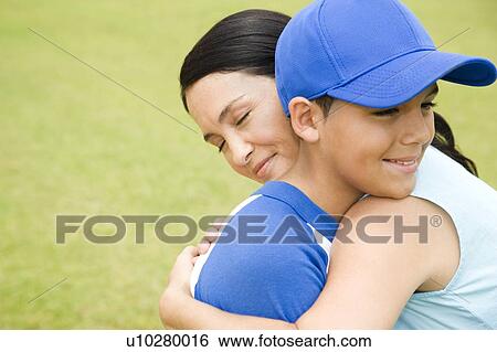 Stock Photograph - Mother hugging son in baseball gear. Fotosearch