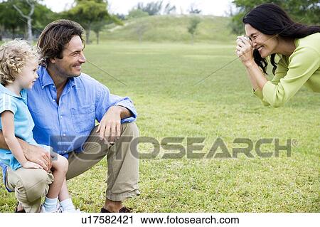 Stock Image - Mother taking photograph of husband and child. Fotosearch