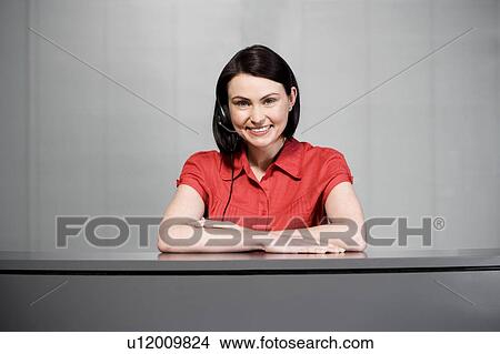 Picture - Office receptionist in a red blouse, smiling. Fotosearch