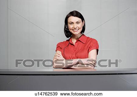 Stock Photo - Office receptionist in a red blouse, smiling. Fotosearch