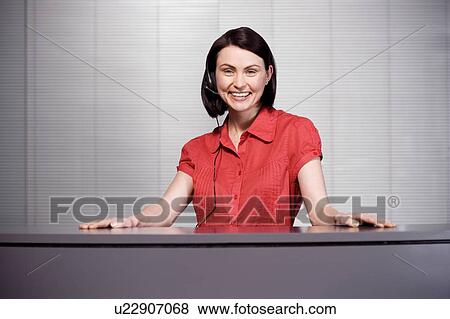 Stock Photo - Office receptionist in a red blouse, smiling. Fotosearch