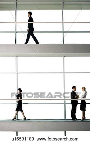 Stock Photo - Office workers walking around modern office building. Fotosearch
