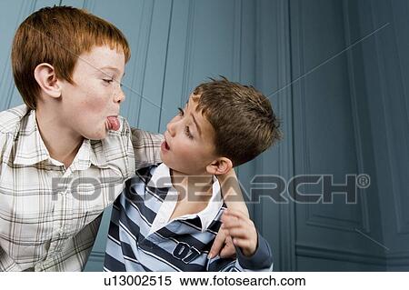 Stock Photography - older boy poking tongue out at younger boy. Fotosearch