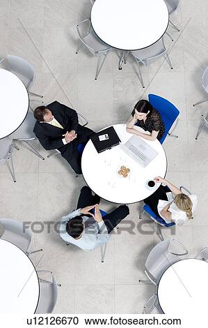 Stock Image - Overhead view of informal business meeting at table of staff canteen. Fotosearch