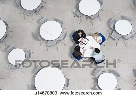 Stock Image - Overhead view of informal business meeting at table of staff canteen. Fotosearch