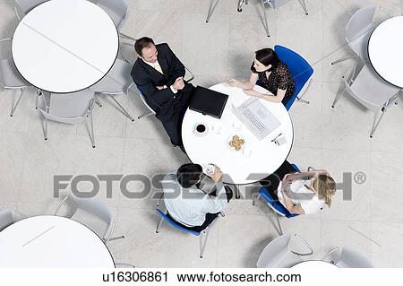 Stock Image - Overhead view of informal business meeting at table of staff canteen. Fotosearch